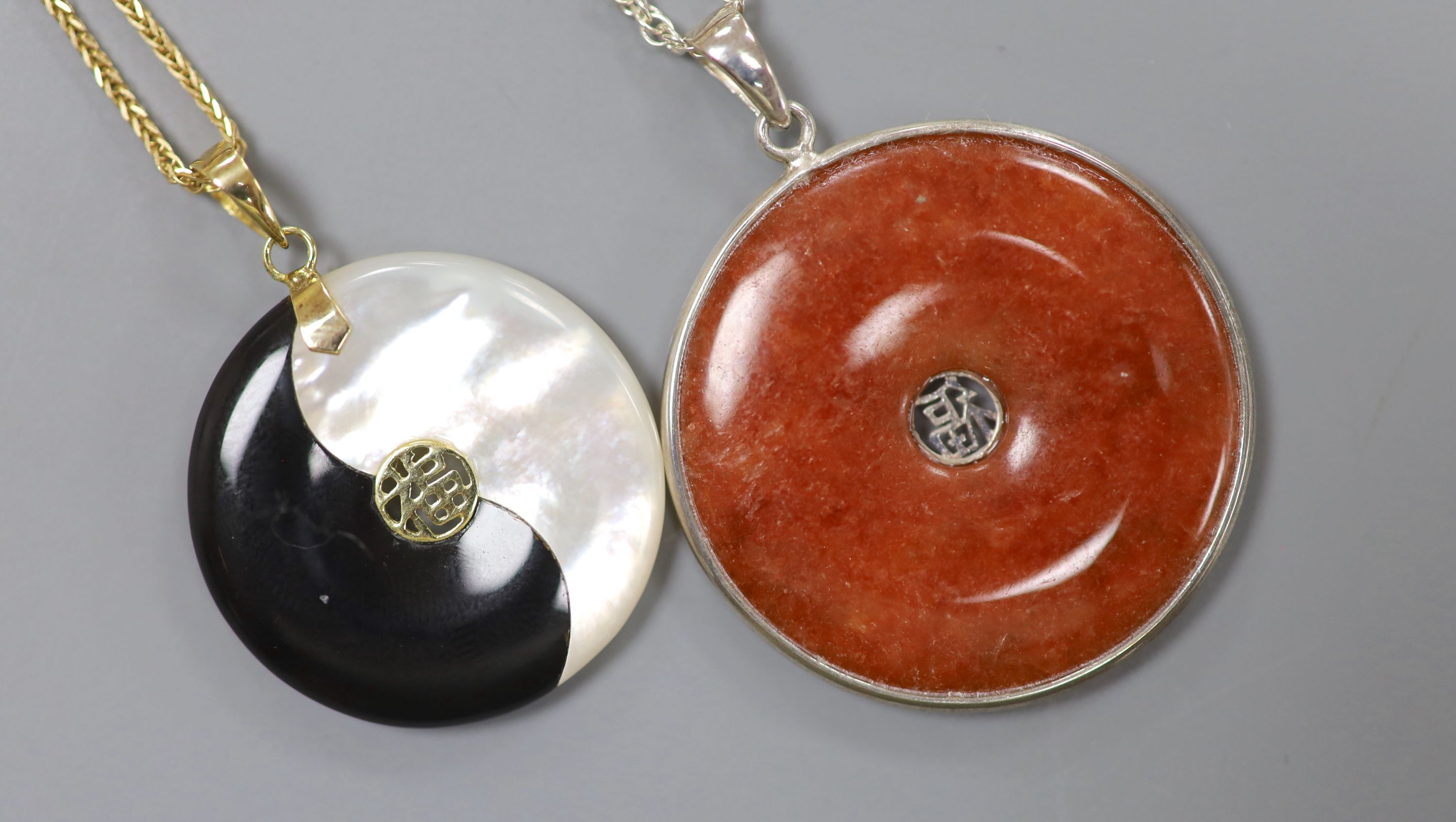 A Chinese gold-mounted black and mother of pearl Yin Yang pendant on 9ct gold chain and a silver-mounted agate disc pendant